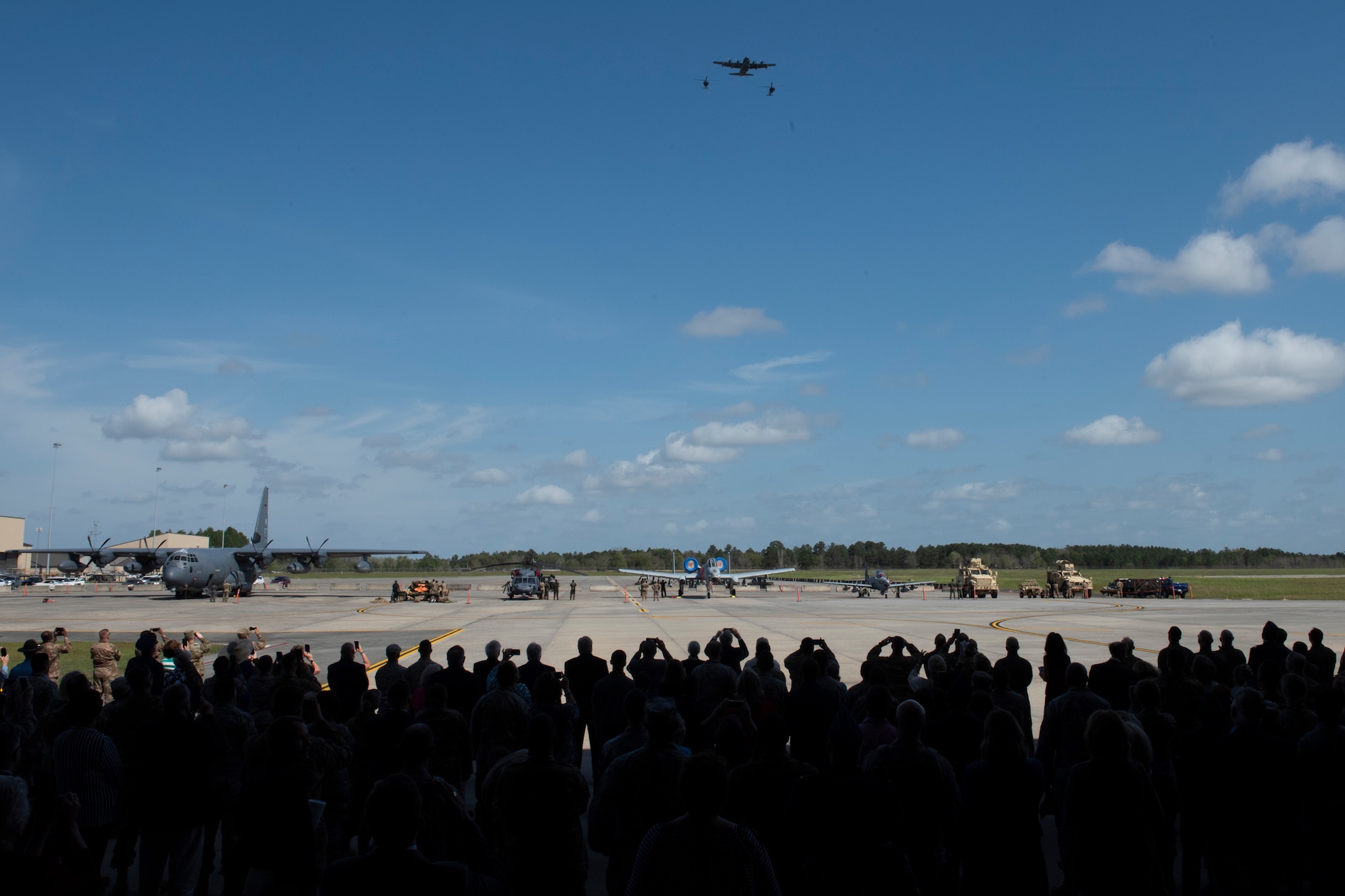 Guests at the W. Parker Greene Celebration of Life ceremony, look up as aircraft fly over on Mar. 14, 2019, at Moody Air Force Base, Ga. The memorial concluded with an HC-130J Combat King II and two HH-60G Pave Hawks in aerial refueling formation and was followed by four A-10C Thunderbolt IIs in a Missing Man formation.(U.S. Air Force photo by Airman 1st Class Joseph P. Leveille)