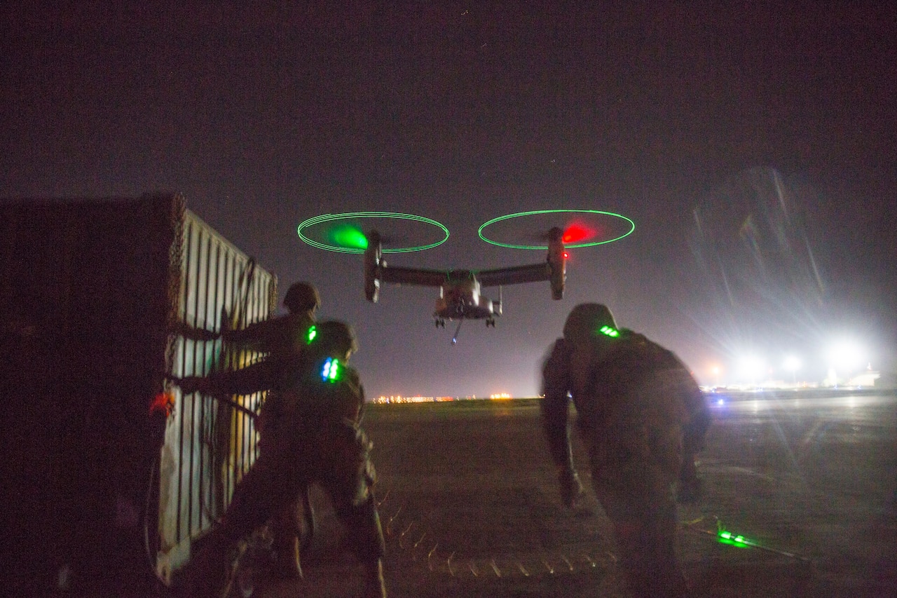 Marines run toward hovering aircraft