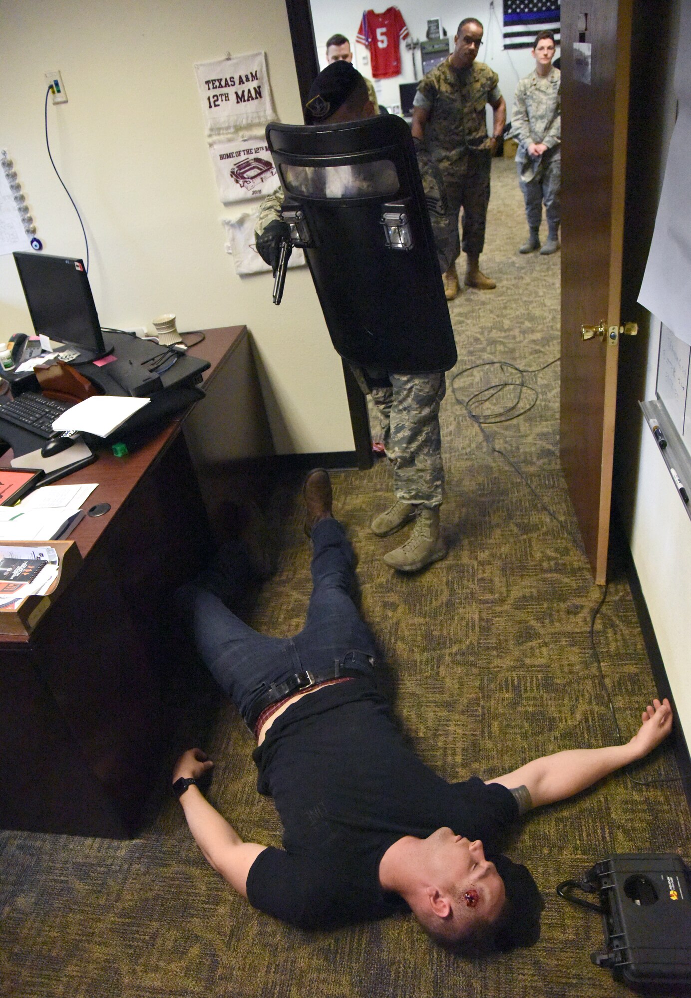U.S. Air Force Staff Sgt. James Vaughan, IV, 81st Security Forces Squadron unit trainer, secures the room as Staff Sgt. Zachary Vega, 81st SFS unit scheduler, portrays the "shooter" lying dead on the floor during an 81st SFS active shooter training demonstration at Keesler Air Force Base, Mississippi, March 14, 2019. The scenario included a disgruntled Airman with marital problems and a pending administrative discharge who ran the entry gate which then escalated to an active shooter situation. Leadership attended the event, which is one of several in recognition of the Year Of The Defender, to observe what steps Keesler Defenders take during a high intensity situation, such as an active shooter, in preparation for real-world situations. Tech. Sgt. Anthony Horton, 81st SFS training NCO in charge, said that the demonstration provided defenders with a realistic scenario that encompassed baseline first responder skills and effectively breeds multi-agency cooperation toward the common goal of minimizing casualties and neutralizing the threat expeditiously. (U.S. Air Force photo by Kemberly Groue)