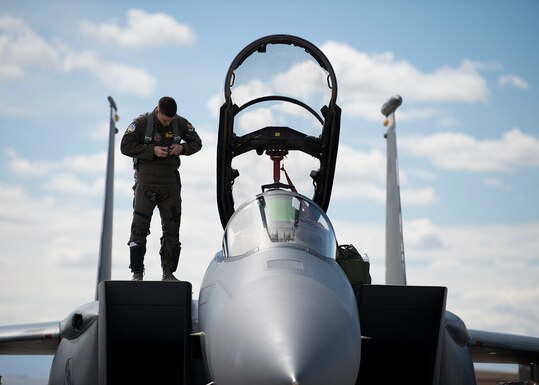 U.S. Air Force 1st Lt. Mathew Clutts, a Weapons System Officer (WSO) on an F-15E Strike Eagle fighter jet assigned to the 336th Fighter squadron, buckles up his harness while standing on top of an F-15E at Nellis Air Force Base, Nev., March 12, 2019. A WSO’s job is to select targets and navigate with the aid of a moving map display, produced by an AlliedSignal remote film strip reader. 