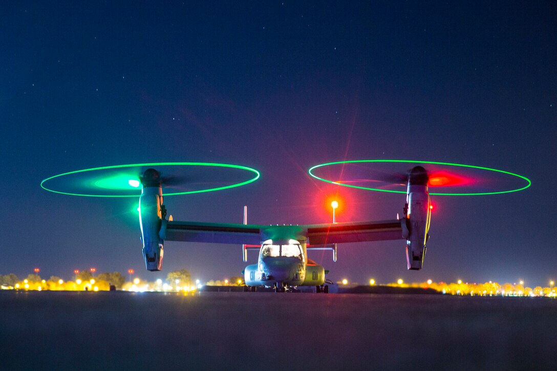 A helicopter parked with it's lights on at night.