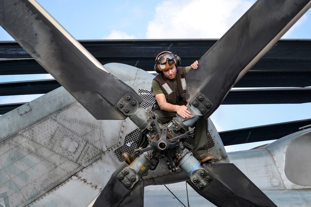 A Marine wipes down a propeller.