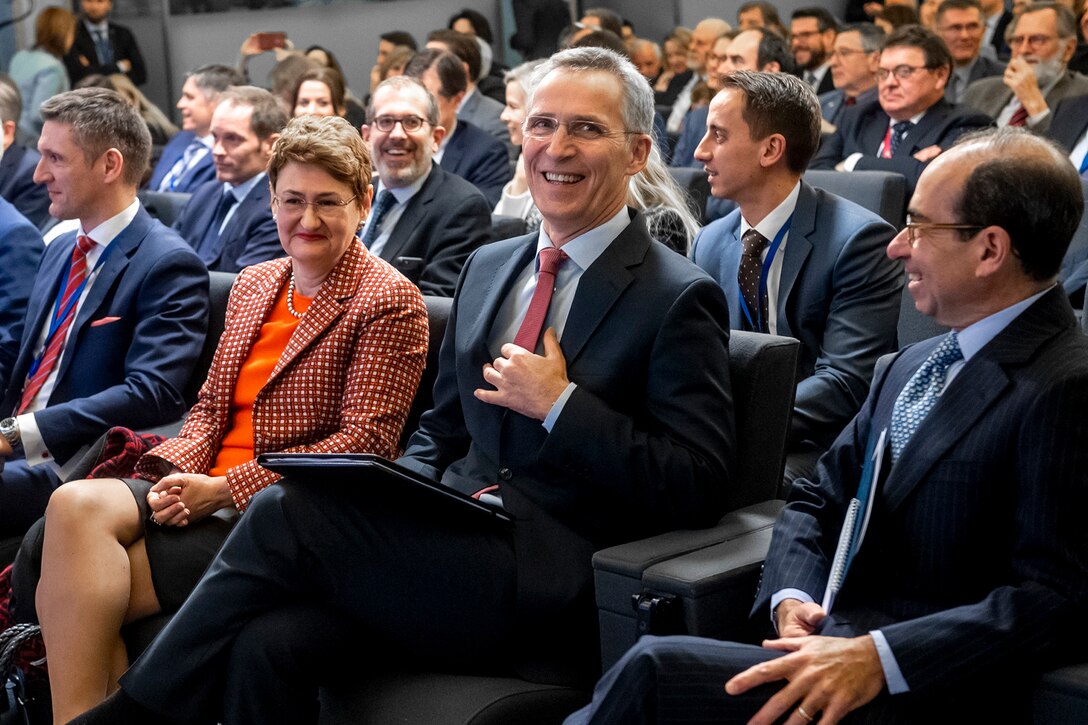 Two men speak in a crowd.