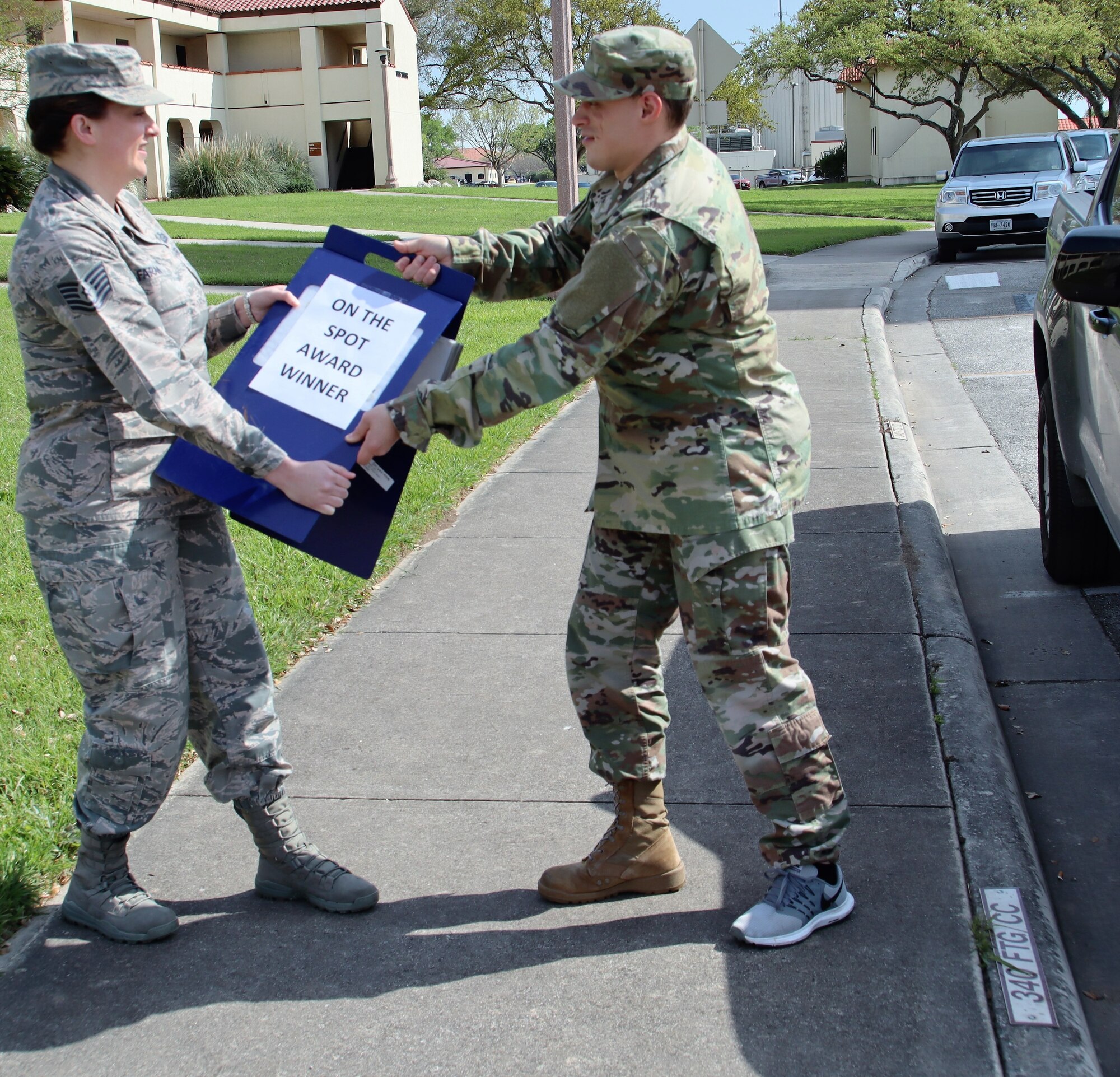Tech. Sgt. Kassandra Farani (left) 340th FTG's February, On the Spot Award winner, claims the award parking sign from January's winner, Tech. Sgt. Brett Daniel. On the Spot Award winners get to park in the commander's parking slot for one week. (U.S. Air Force photo by Janis El Shabazz)