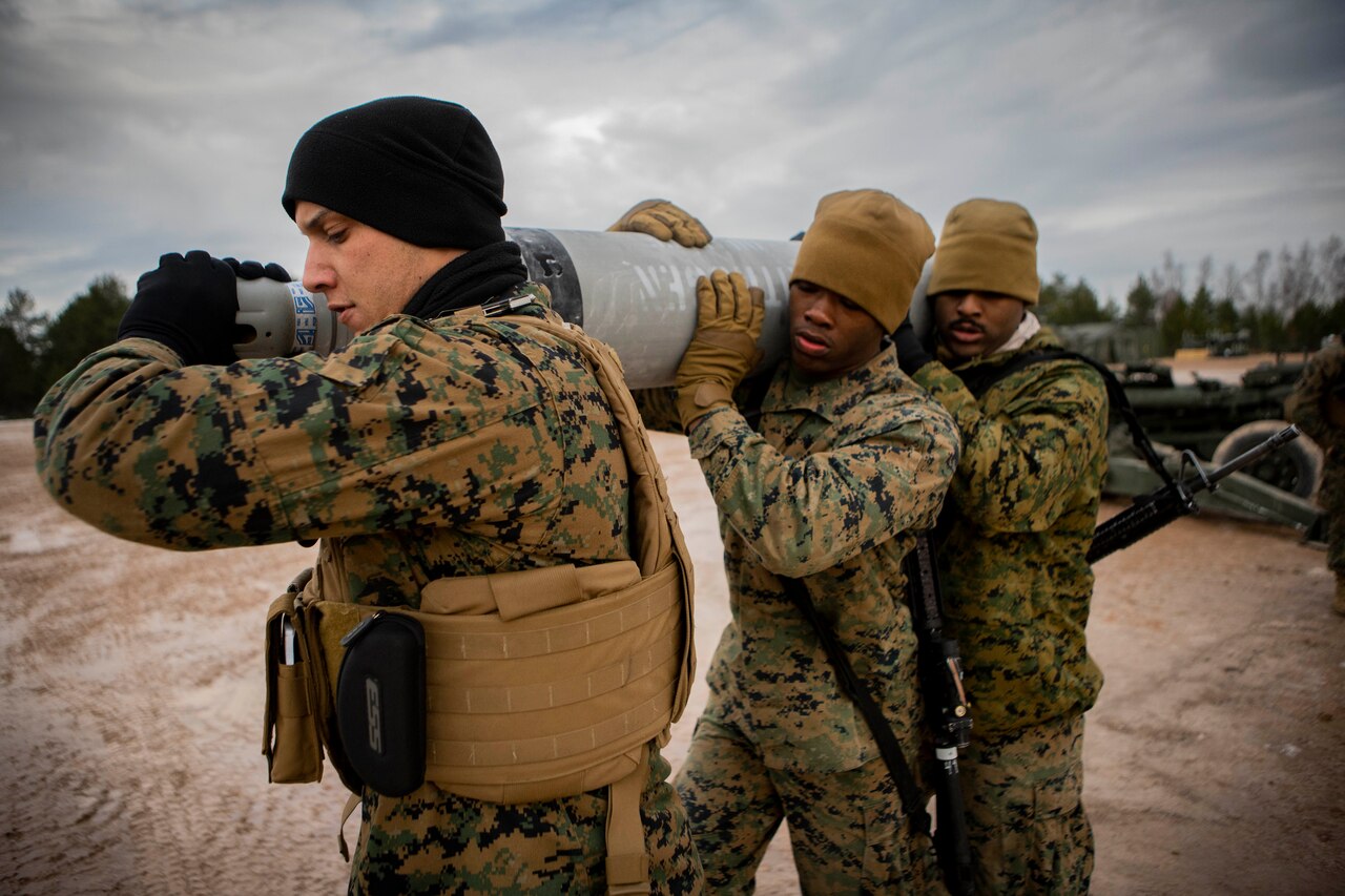 Three Marines carry equipment