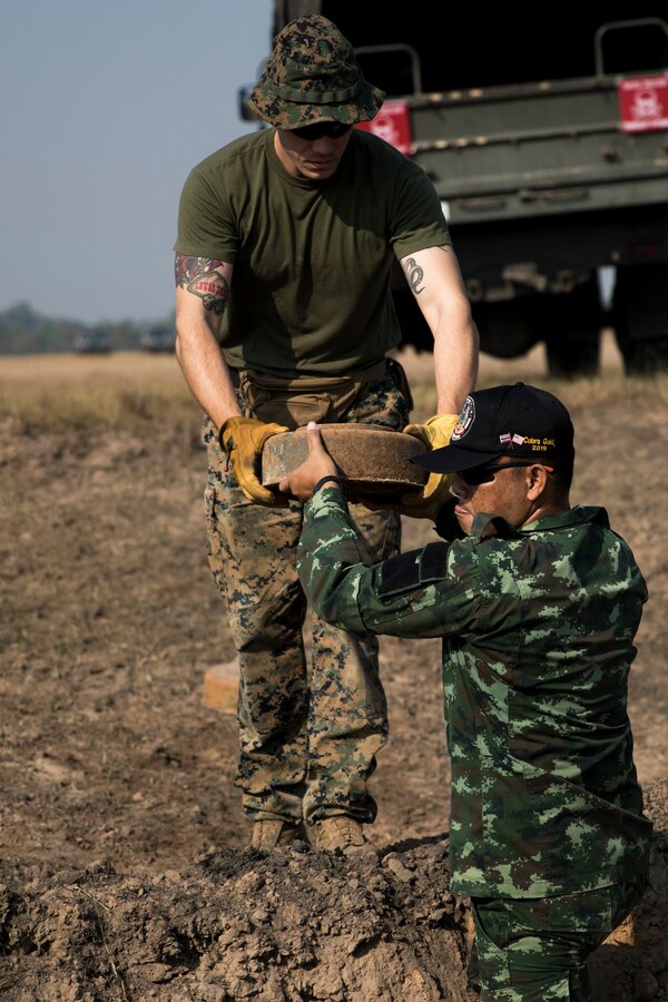 U.S. Marine Corps Sgt. Christopher Piette passes an anti-tank landmine to a Royal Thai Army explosive ordnance disposal technician during Cobra Gold 19 Feb. 19, 2019 in the Kingdom of Thailand. U.S. Marines assist the Royal Thai Armed Forces in teaching explosive ordnance disposal courses and disposing landmines. Piette, an EOD technician with 3rd EOD Company, 9th Engineer Support Battalion, is a native of De Pere, Wisconsin. (U.S. Marine Corps photo by Cpl. Jamin M. Powell)