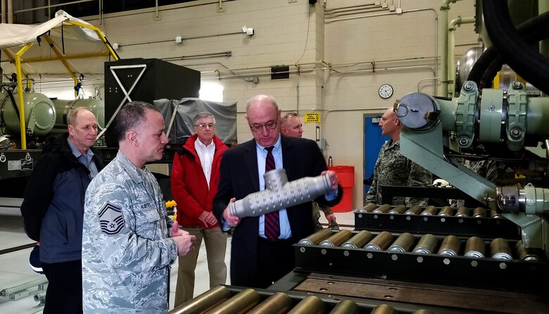 Col. (ret) Joseph Zeis (center), Aerospace and Defense Advisor for Ohio Governor Mike DeWine, examines a section of piping from one of the 910th Airlift Wing's Modular Aerial Spray Systems here, March 13, while Senior Master Sgt. Phil Aliberti, 910th Aerial Spray Maintenance Chief, explains how the piece was cast using advanced manufacturing techniques.