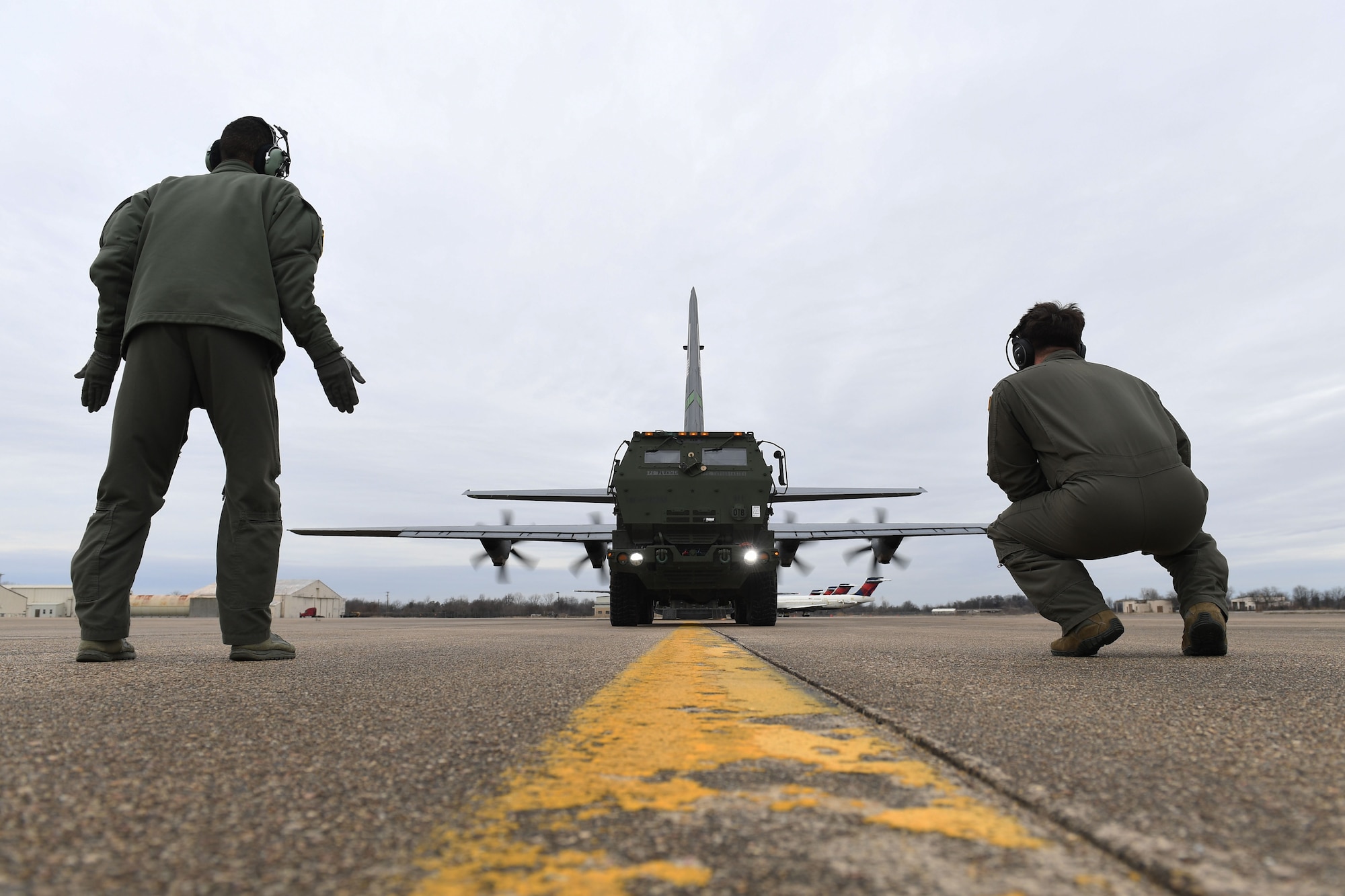 Two Airmen onload a vehicle to a C-130J.