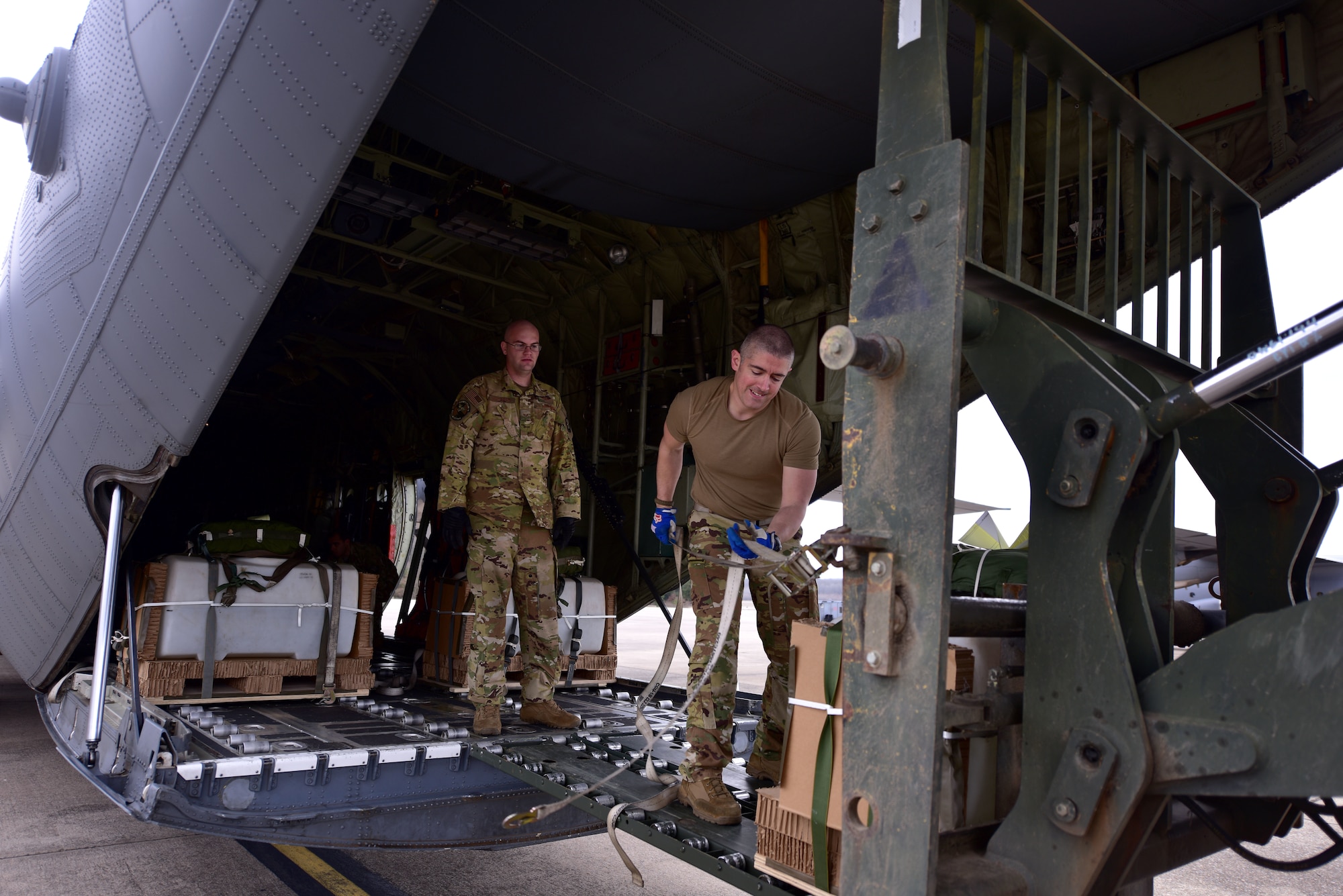 Two Airmen onload equipment to a C-130J.