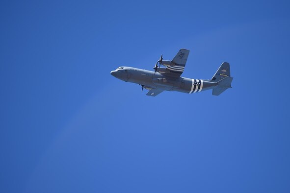 A C-130J flies overhead.