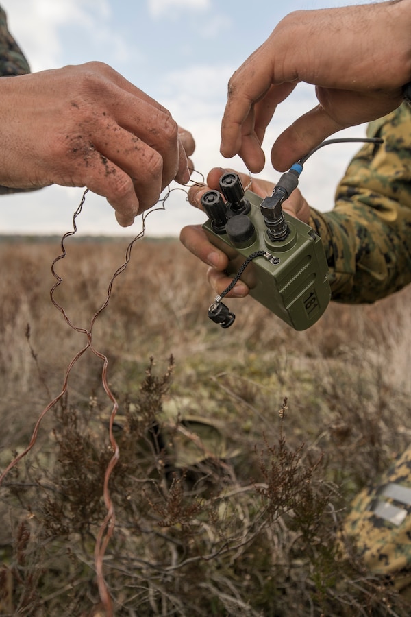 U.S. Marine Corps Staff Sgt. Joseph Martinez (left), an explosive ordnance disposal Marine attached to Headquarters Battery, 14th Marine Regiment, 4th Marine Division, helps a Marine tie blasting-cap wires to an electronic receiver at a demo range at Adazi Training Area, Latvia, March 8, 2019, during exercise Dynamic Front 19. Exercise Dynamic Front 19 includes approximately 3,200 service members from 27 nations who are observing or participating from Grafenwoehr Training Area, Germany; Riga, Latvia; and Torun, Poland; during March 2-9, 2019. Dynamic Front is an annual U.S. Army Europe exercise focused on the readiness and interoperability of U.S. Army, joint service, and allied and partner nations’ artillery and fire support working together in a multinational environment. (U.S. Marine Corps photo by Cpl. Niles Lee)