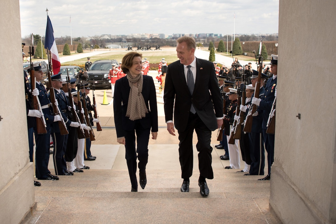 A man and a woman walk up some steps at the Pentagon.