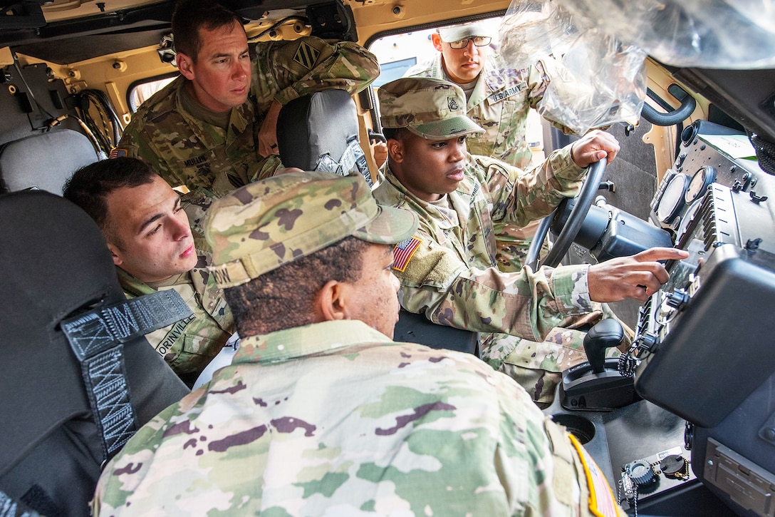 Soldiers examine touch screens inside a new military vehicle.