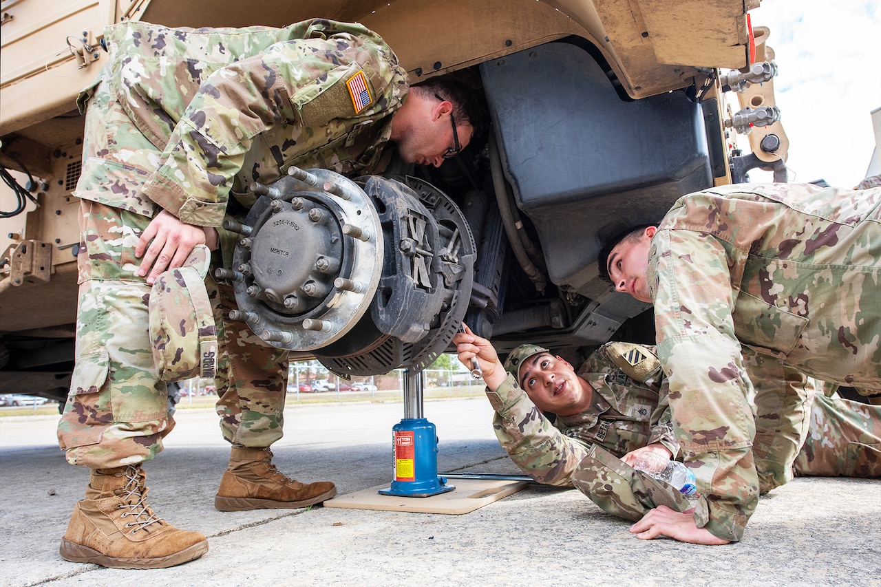 Soldiers work under a tactical vehicle.