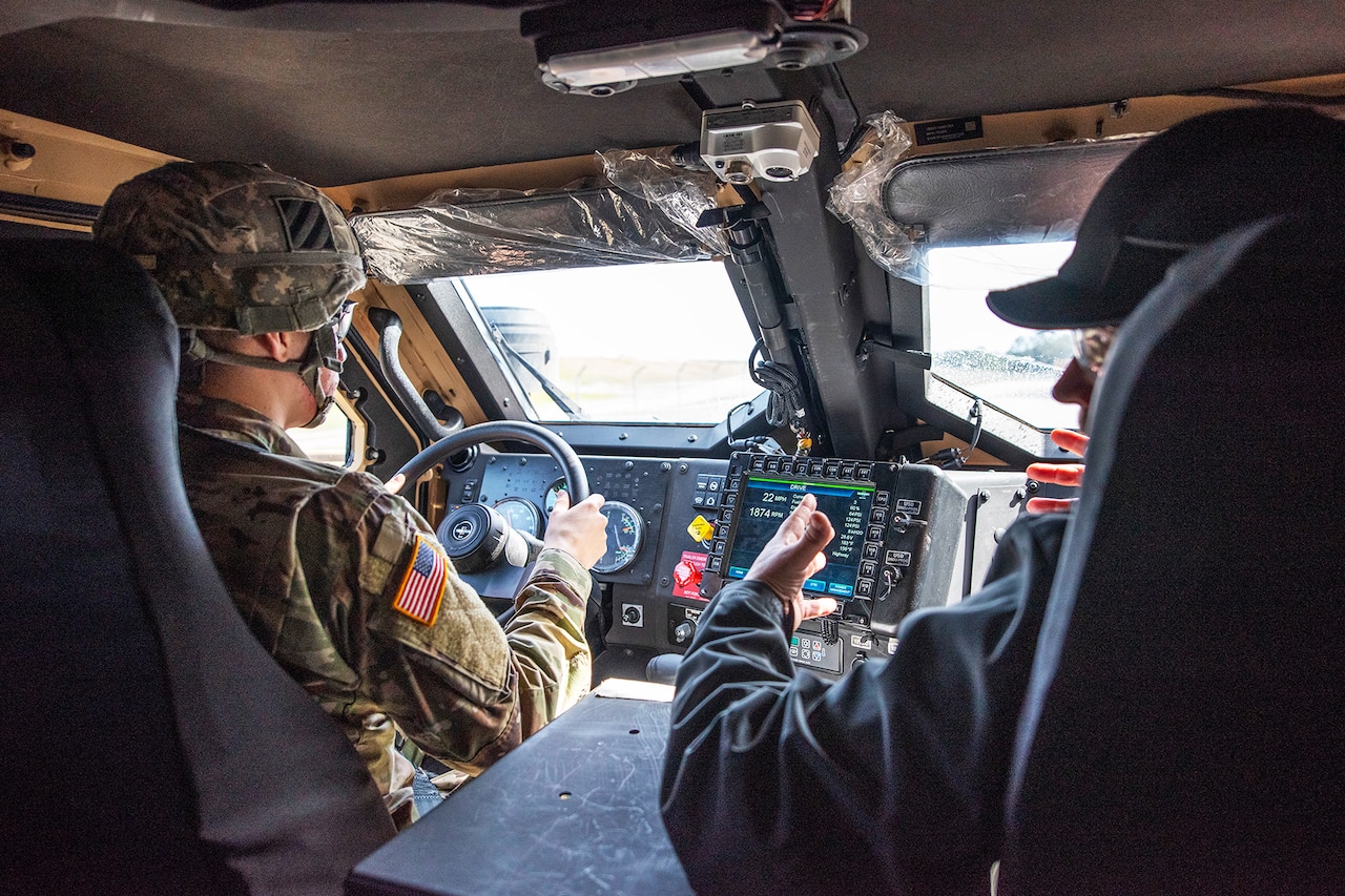 A soldier drives a new tactical vehicle as a contractor talks to rear seat passengers.