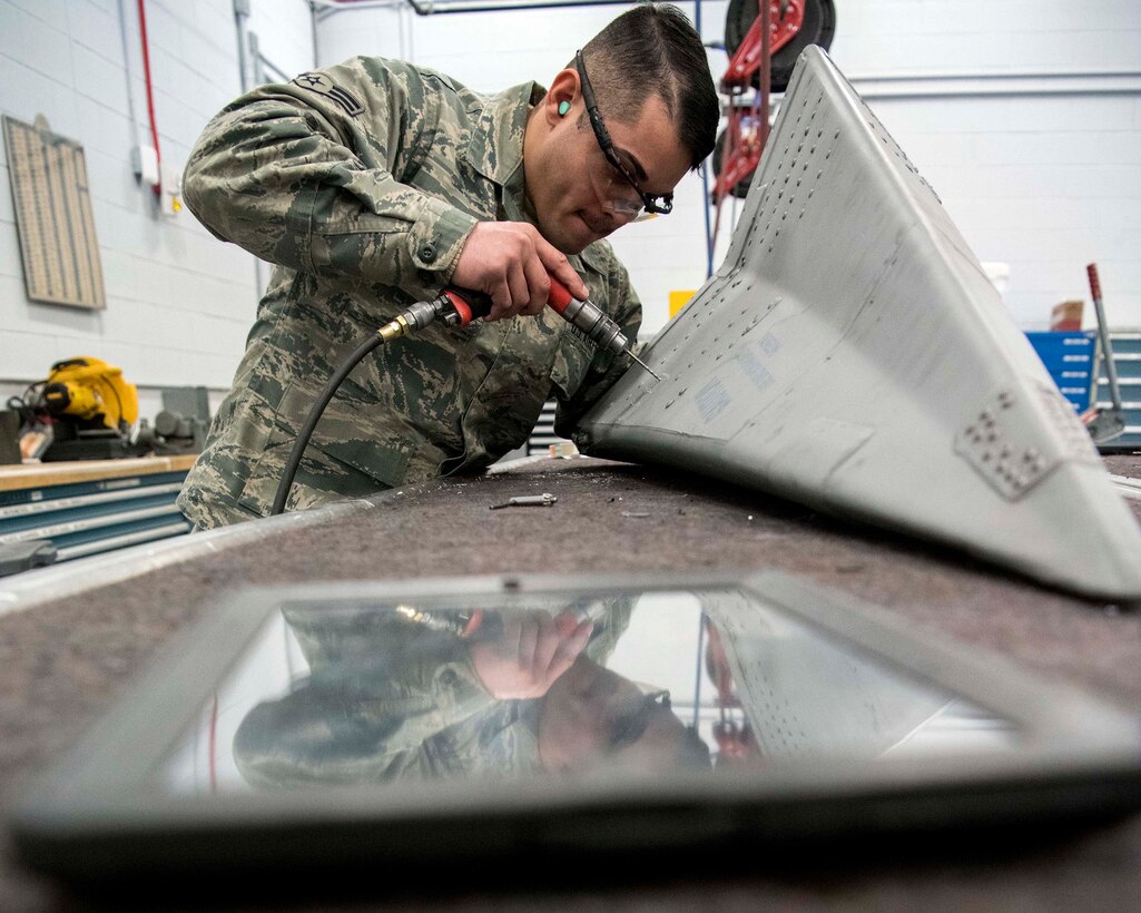 Airman 1st Class Jose Lozada Jr., a sheet metal technician with the Massachusetts Air National Guard's 104th Fighter Wing, removes rivets to repair cracks on an F-15 Eagle tail cone in Westfield, Massachusetts, March 3, 2019. Lozada, who also has automotive body and repair jobs on the civilian side, said that even after a little more than a year of working in aircraft structural maintenance, the thrill of being around F-15s still hasn't worn off. "Working on a jet still leaves me speechless," he said. "Just to even think that I went from something so small [automobiles] to working on something so big."