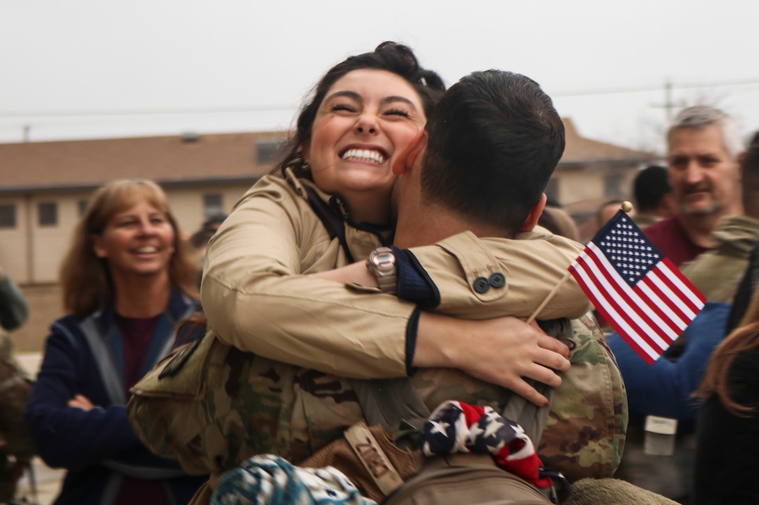 A woman smiles as she hugs a man.