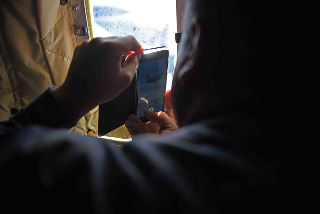 A member of the Romanian air force records a video of a Romanian air force F-16 flying in formation with KC-135 Stratotanker from RAF Mildenhall, England, during training over the skies of Romania, March 13, 2019. The training was an example of U.S. and NATO allies sharing a commitment to promote peace and stability through developing their relationship and communication process. (U.S. Air Force photo by Airman 1st Class Brandon Esau)