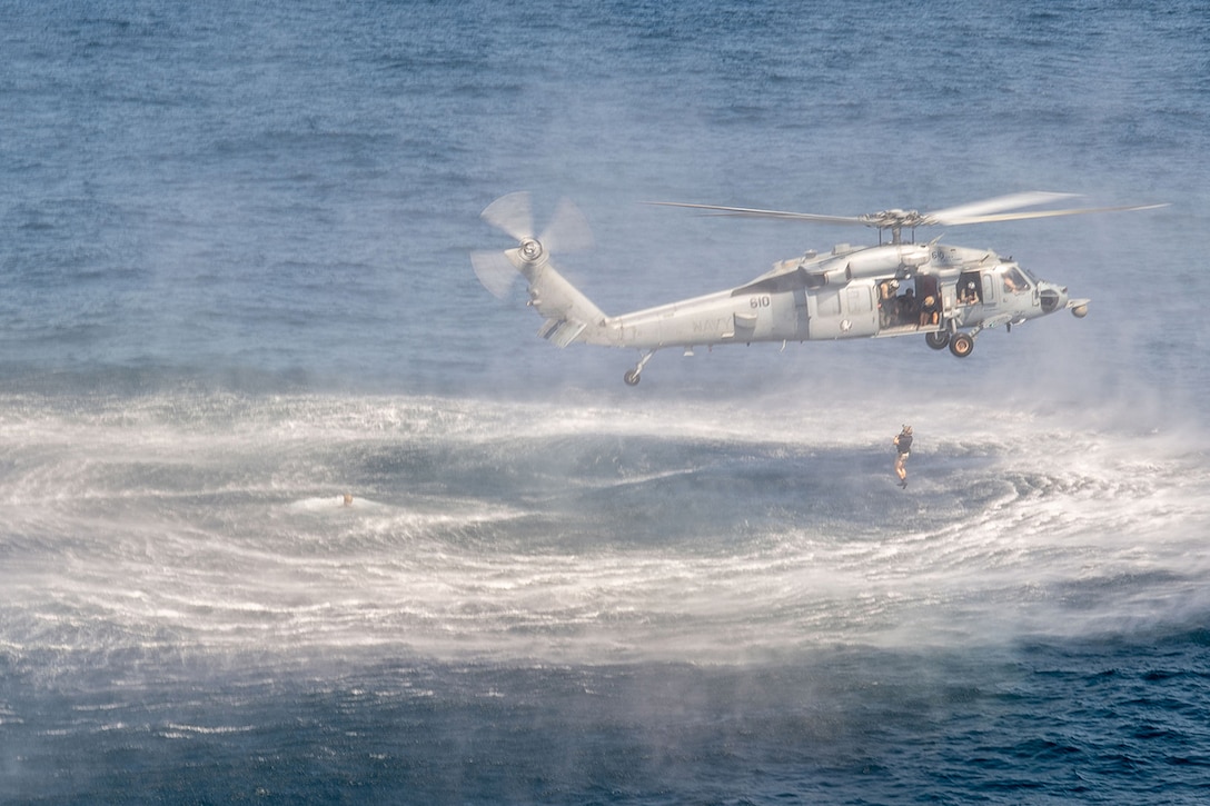 A helicopter flies low over water.