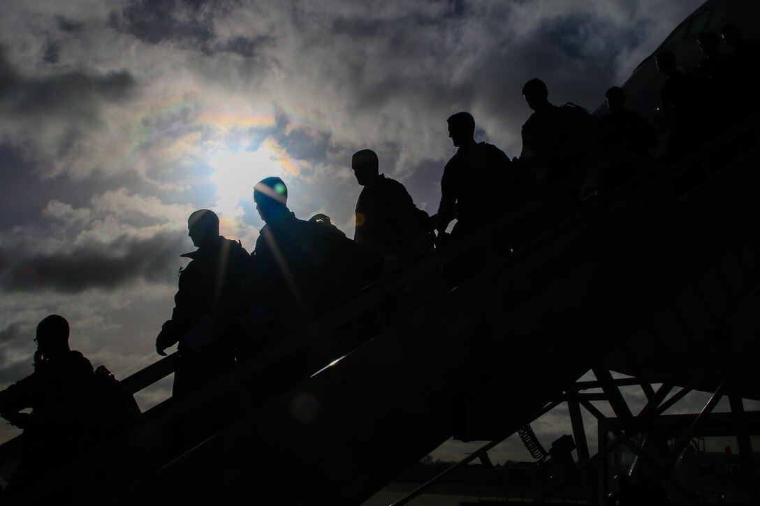 Service members walk off a plane.