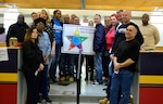DLA Troop Support Construction and Equipment supply chain employees pose for a photo during the spring clean-up event in Building 3 March 20, 2019 in Philadelphia. The employees participated in the housekeeping component of the VPP program, an OSHA led initiative, that encourages cooperative efforts between management, employees and unions to reduce mishaps, pest and improve workplace safety. (Photo by Alexandria Brimage-Gray).