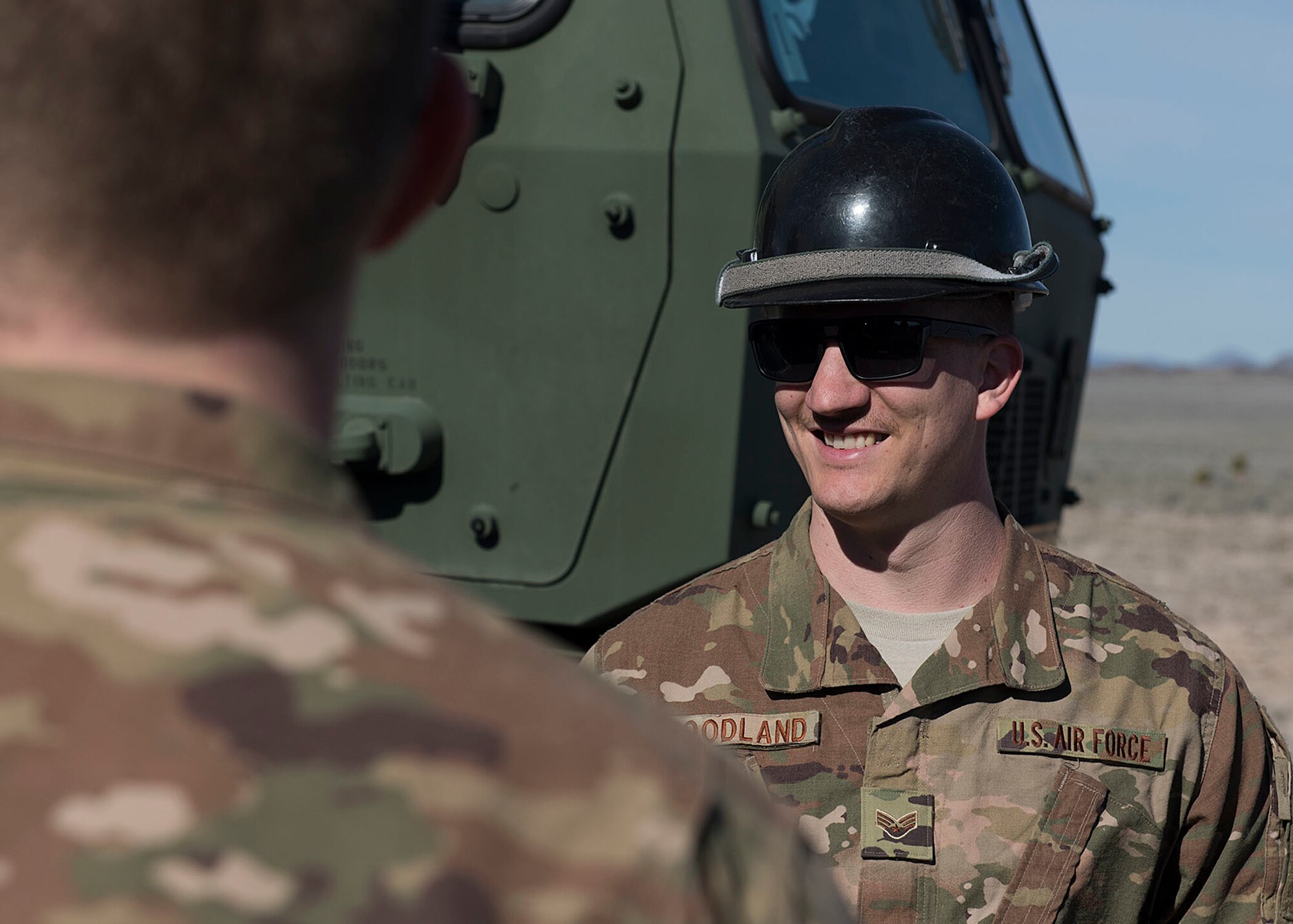 An Airman wears a hardhat while smiling.