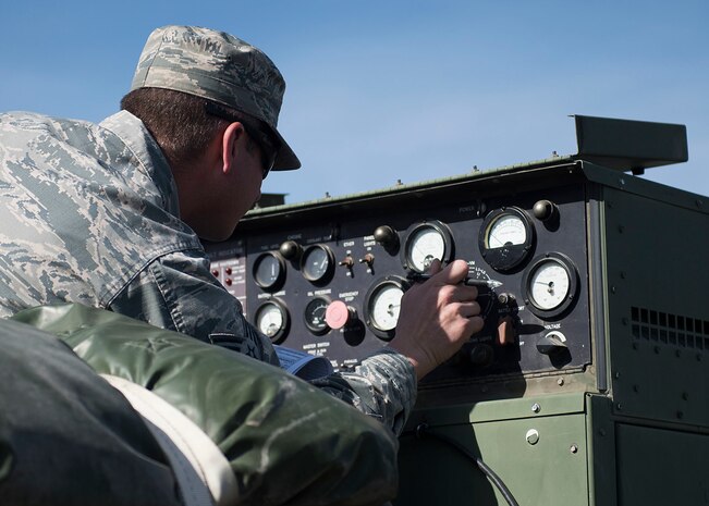 An Airman adjusts dials on a panel.