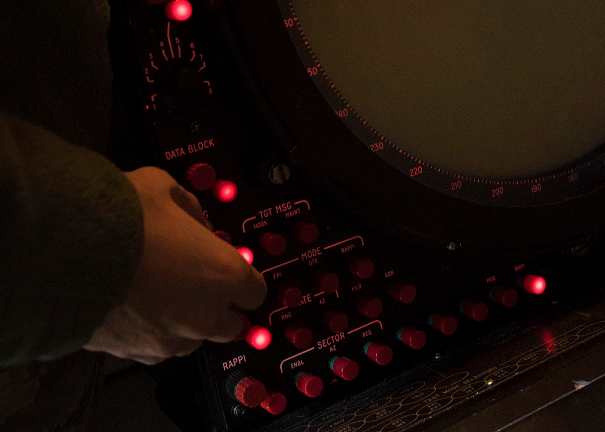 An Airman turns a red dial on a panel.