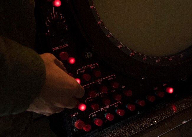 An Airman turns a red dial on a panel.