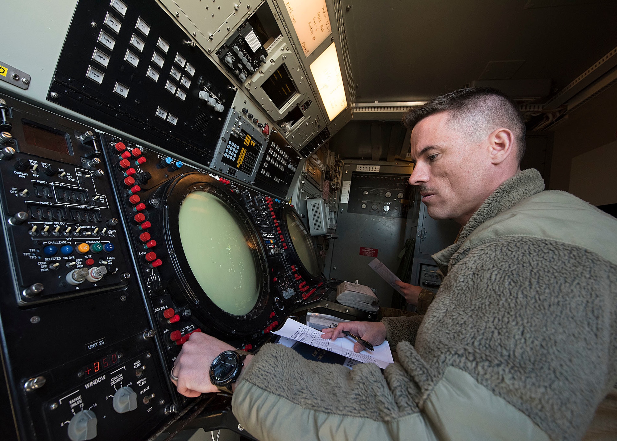 An Airman adjusts dials on  a radar.