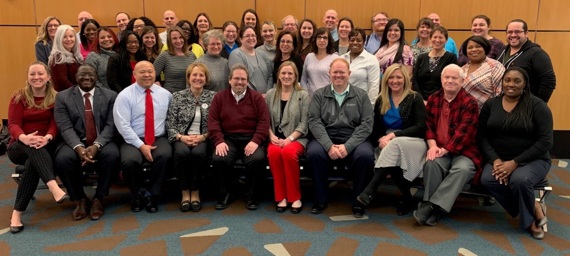 43 people grouped together smiling at camera for photo