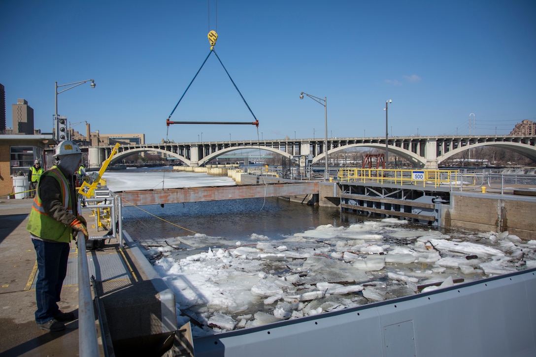 man oversees crane ready to lift bulkhead on river