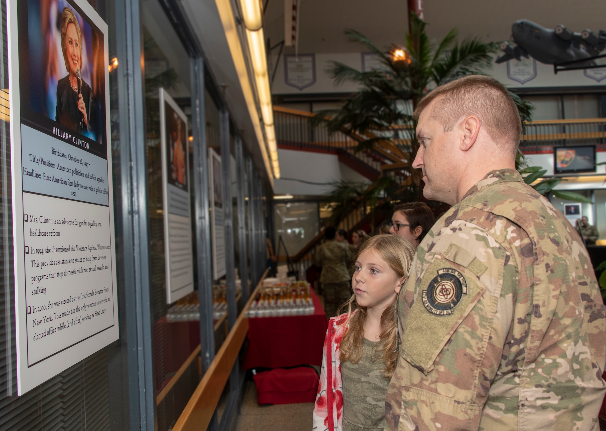 U.S. Air Force Senior Master Sgt. Michael Dean, 321st Air Mobility Operations Squadron, and his daughter Morgan, read facts about former United States Secretary of State, Hillary Clinton, during a Women’s History Month social gathering, March 20, 2019, at Travis Air Force Base, California. Since 1987, the month of March has been designated to celebrate the historical and ongoing achievements and contributions of women. Members of the Women Inspiring the Next Generation’s Success committee were responsible for organizing the event which included an exhibit highlighting extraordinary female heroes and featured speakers prominent in the Travis community. (U.S. Air Force photo by Heide Couch)