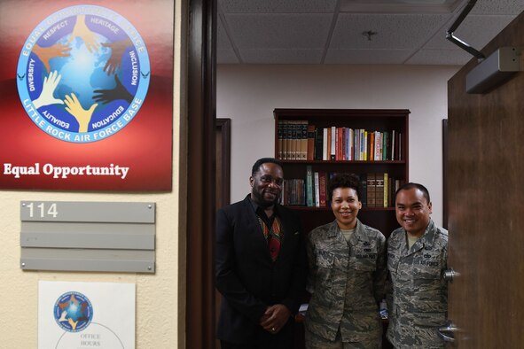 Two men and a woman stand in an open doorway.