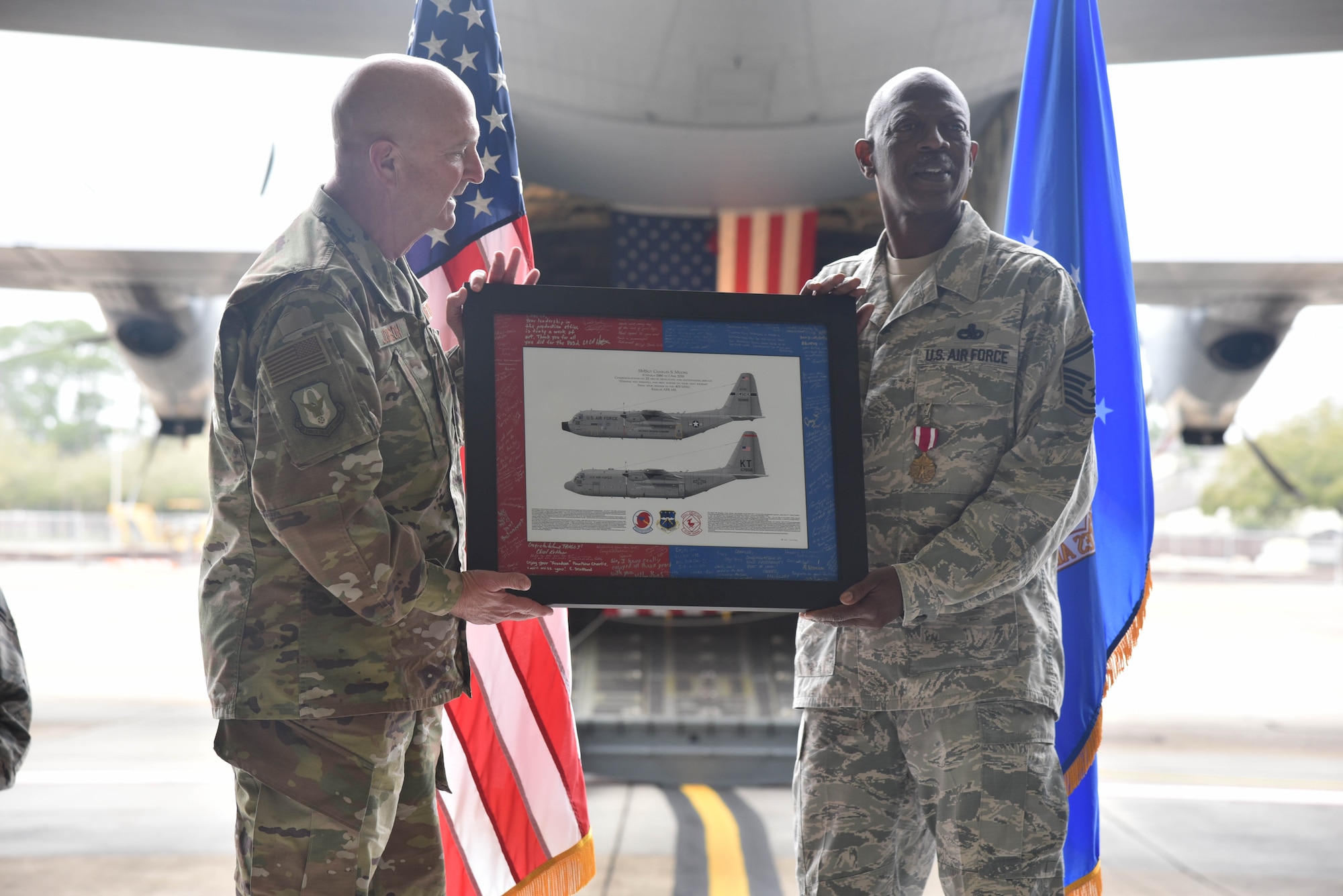 Senior Master Sgt. Charles Moore, 803rd Aircraft Maintenance Squadron production superintendent, accepts framed C-130J Super Hercules aircraft artwork from Col. Jay Johnson, 403rd Maintenance Group commander, during Moore's retirement ceremony, March 8, 2019.  Moore officially retires April 1, 2019, after serving 33 years in the Air Force Reserve. (U.S. Air Force photo by Tech. Sgt. Michael Farrar)
