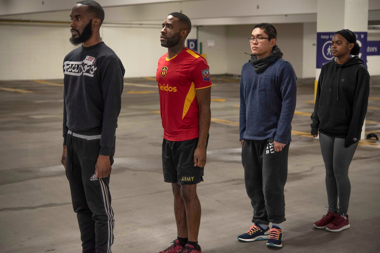 Four recruits stand at attention in formation.