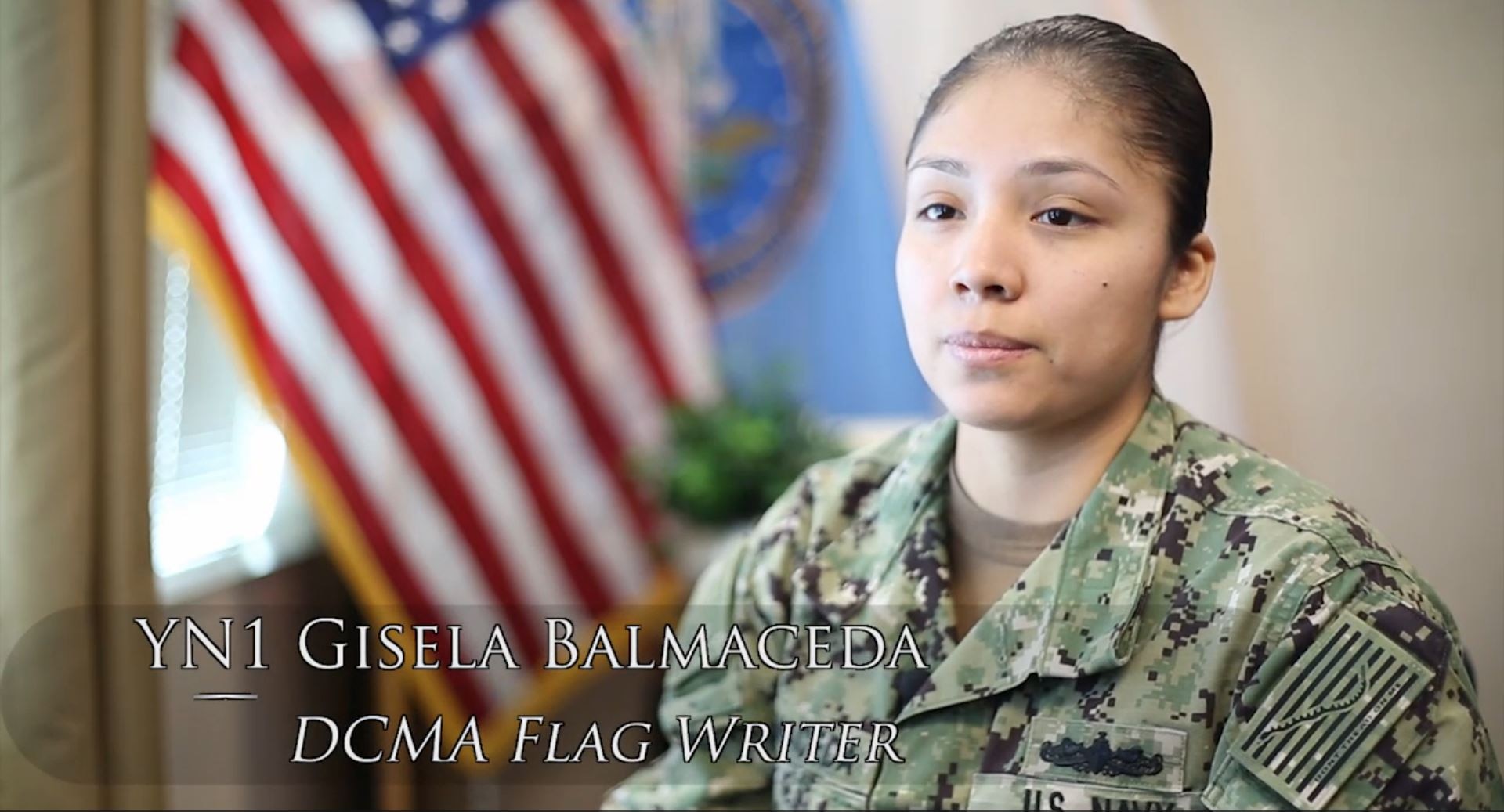 Woman in Navy uniform sits in front of camera.