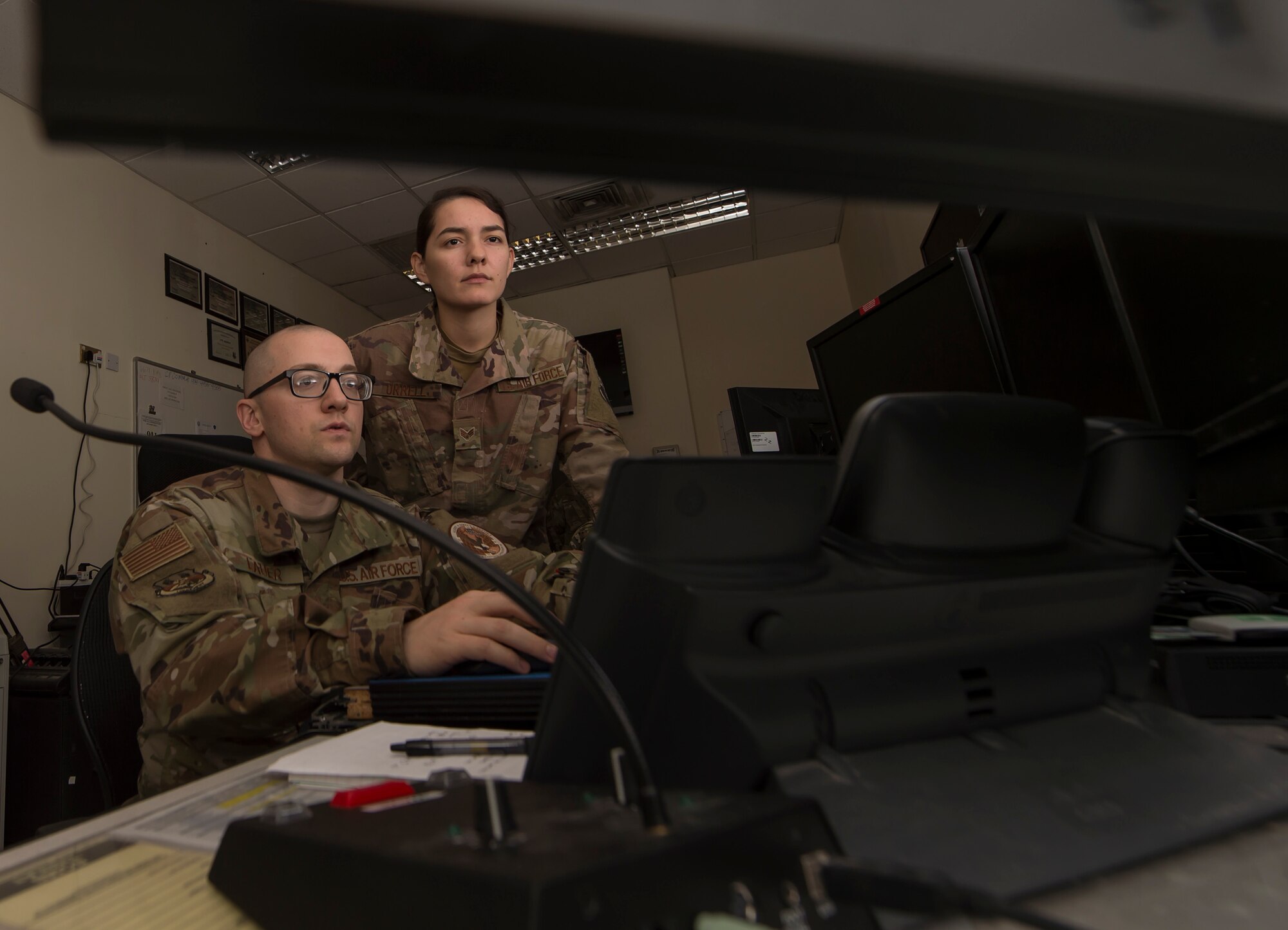 Tech. Sgt. Edward Lauer, 379th Air Expeditionary Wing (AEW) Command Post NCO in charge of command and control operations, briefs Senior Airman Anelle Orrell, 379th AEW Command Post controller, March 22, 2019, at Al Udeid Air Base, Qatar. Airmen from the command post are responsible for gathering and relaying information to entities across base to include aircraft maintenance requirements, security forces incidents, and notifications that ensure the safety of Airmen and other assets on base. (U.S. Air Force photo by Tech. Sgt. Christopher Hubenthal)