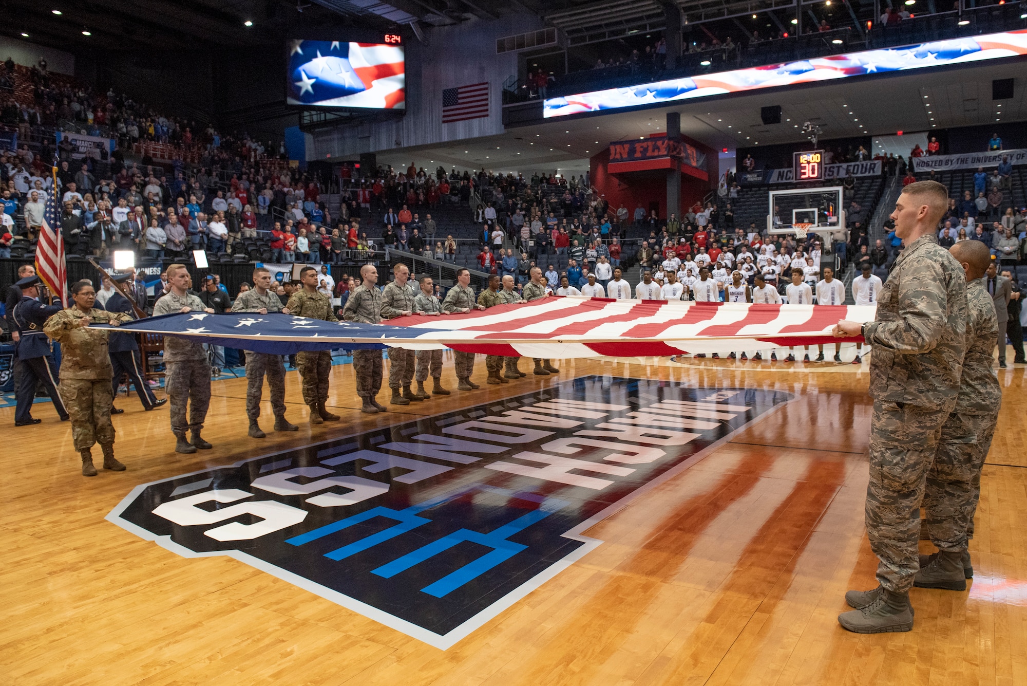 Airmen from Wright-Patterson Air Force Base, Ohio hold a large garrison-size American flag during the presentation of the colors and singing of the national anthem at the NCAA First Four Tournament March 19, 2019. (U.S. Air Force photo by Michelle Gigante)