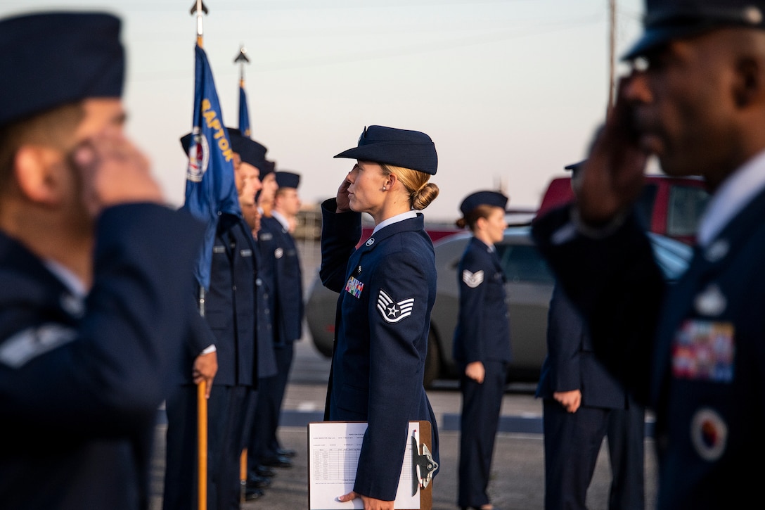 A group of airmen stand in rows saluting.