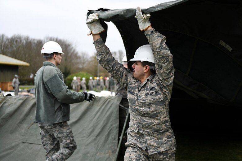 Airman George Ramirez, 48th Civil Engineering Squadron heating, ventilation, and air conditioning technician, puts the main cover fabric over a Tent Extendable Modular Personnel tent frame during an inventory check and training day at Royal Air Force Feltwell, England, March 22, 2019. A TEMPER tent is a highly versatile design suitable for a wide range of environments and can be assembled from a standard module to a multitude of configurations.  (U.S. Air Force photo by Senior Airman Malcolm Mayfield)