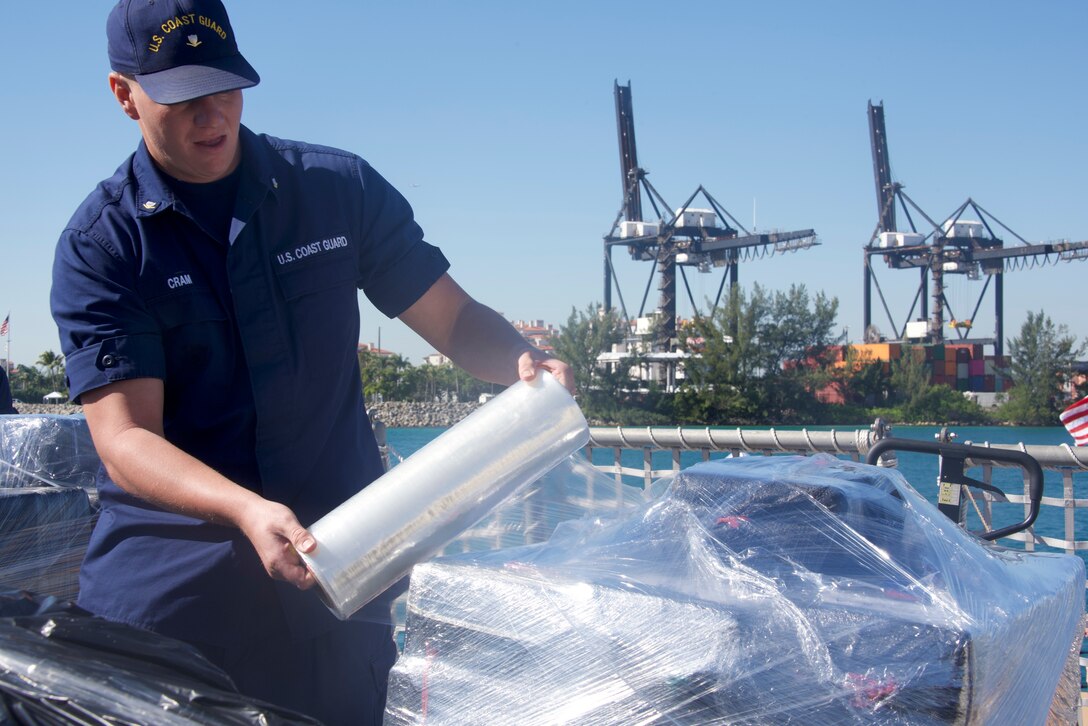 Coast Guard Petty Officer 3rd Class Mason R. Cram wraps a palette of cocaine in preparation for a drug offload Mar. 22, 2019 at Coast Guard Base Miami Beach.