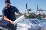 Coast Guard Petty Officer 3rd Class Mason R. Cram wraps a palette of cocaine in preparation for a drug offload Mar. 22, 2019 at Coast Guard Base Miami Beach.