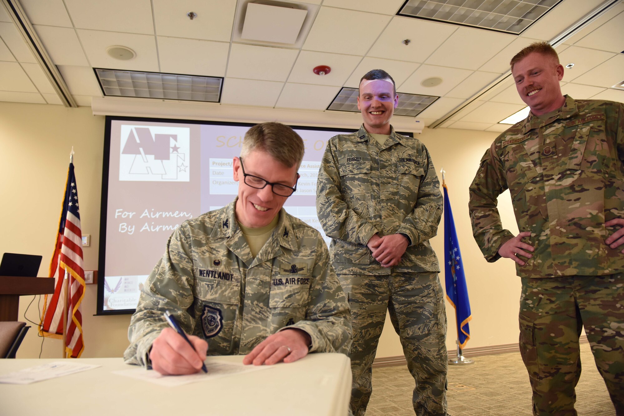 Col. Trevor Wentlandt, 460th Mission Support Group commander, fills out his 2019 Air Force Assistance Fund donation form during the Team Buckley AFAF Campaign kick-off event March 20 at the base chapel, while Capt. Kevin Feiszli (center) and Master Sgt. Jason Stonehocker (right), Team Buckley AFAF Project Officers, look on. (U.S. Air Force photo by Master Sgt. Beth Anschutz)