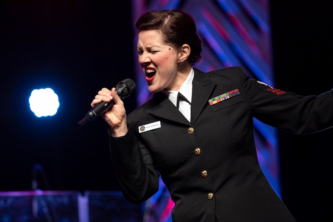 A sailor sings into a microphone.