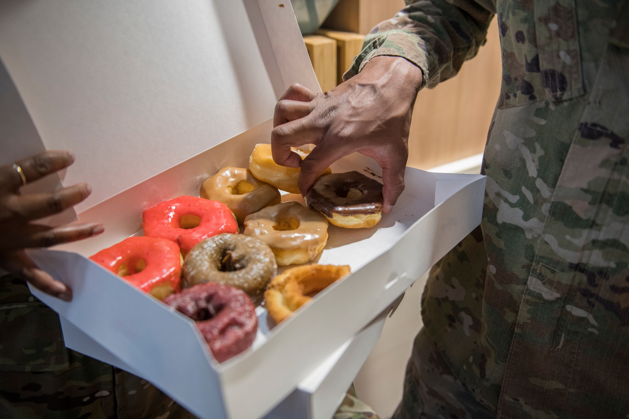 Senior Airman Donovan Stewart, 27th Special Operations Force Support Squadron food service journeyman, takes a donut provided at the Diamonds and Donuts event at Cannon Air Force Base, N.M., March 22, 2019. First sergeants hand-delivered the donuts to Air Commandos as a way to show they care. (U.S. Air Force photo by Airman 1st Class Vernon R. Walter III)