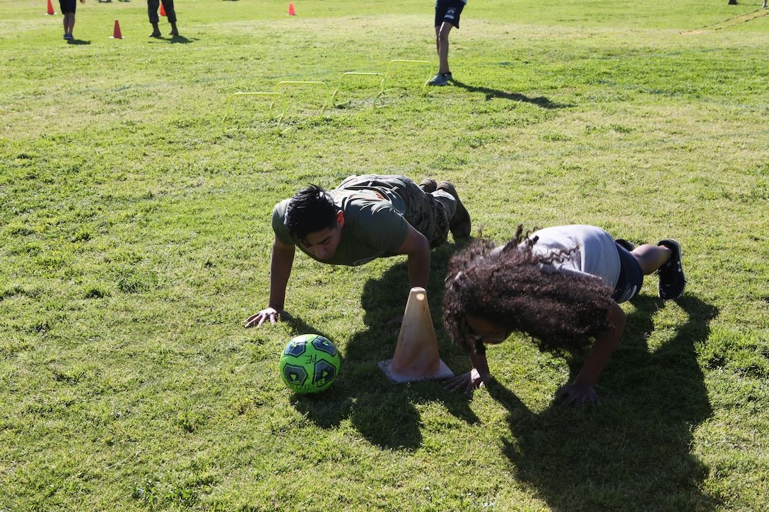 Lance Cpl. Cesar Salais, an aviation supply Marine with Marine Aviation Logistics Squadron (MALS) 16, helps encourage a student with De Portola Middle School during the 9th annual Marine Corps Fitness Challenge in San Diego, Calif., March 22, 2019. During the challenge, MCAS Miramar Marines led students through four different physical training courses throughout their physical education periods to give the students a better outlook on physical fitness. (U.S. Marine Corps photo by Lance Cpl. Raynaldo Ramos)