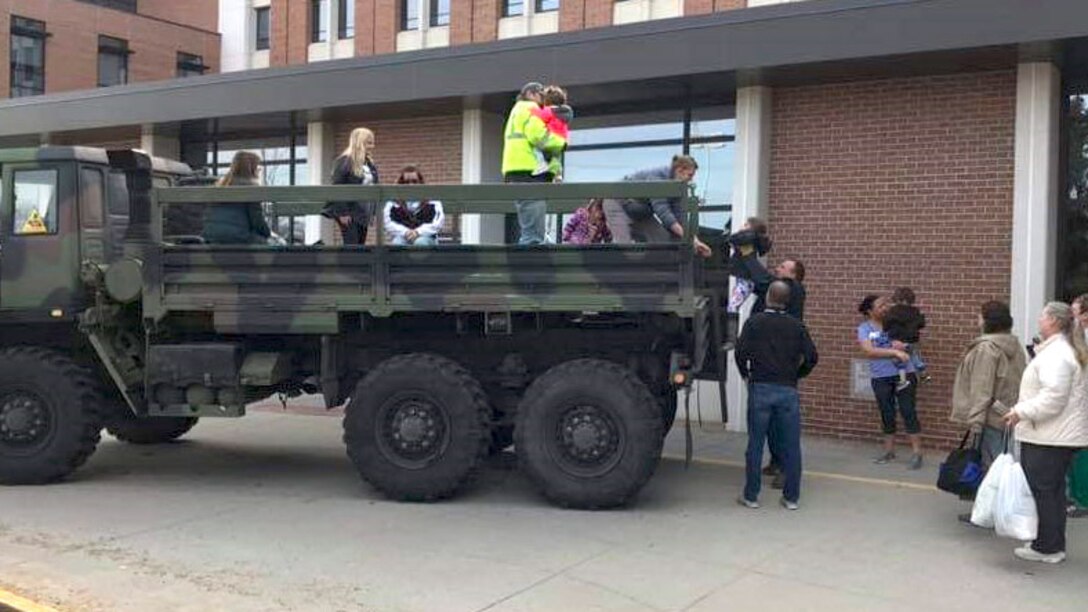 Stranded hospital staff and family members are loaded into a former military truck to be transported home