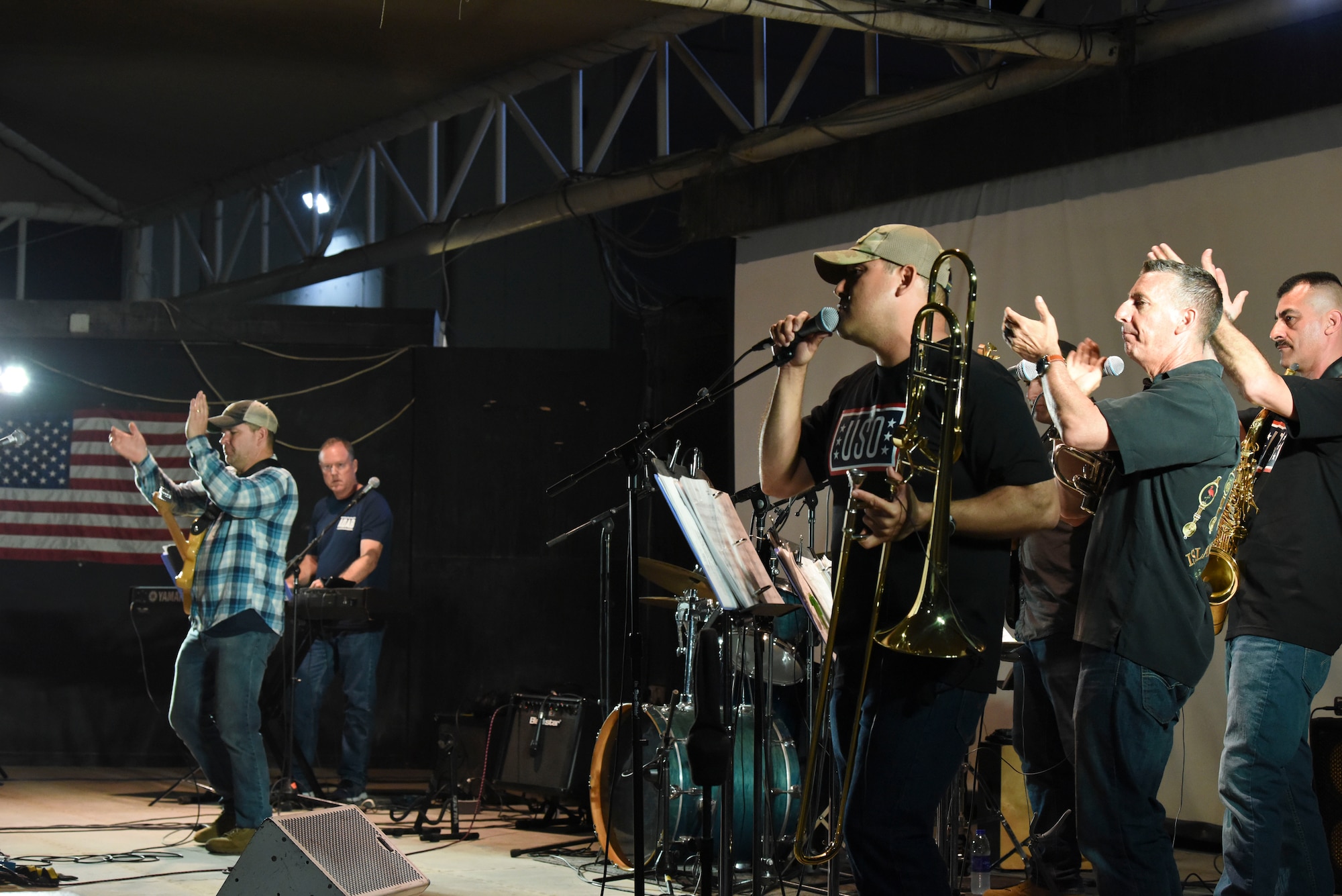 Tech. Sgt. Daniel Olivas performs a song while the rest of the Air Forces Central Command band clap for the crowd of deployed members at Al Dhafra Air Base, United Arab Emirates, Mar. 20, 2019.