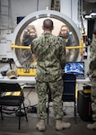 PANAMA CITY, Florida – Research Physiologist Lt. Travis Doggett, center, directs aircrew via radio during simulated flight in the Fluctuating Altitude Simulation Technology (FAST) system Jan. 14, 2019 at Navy Experimental Diving Unit. The system was developed and built by Naval Surface Warfare Center Panama City Division.